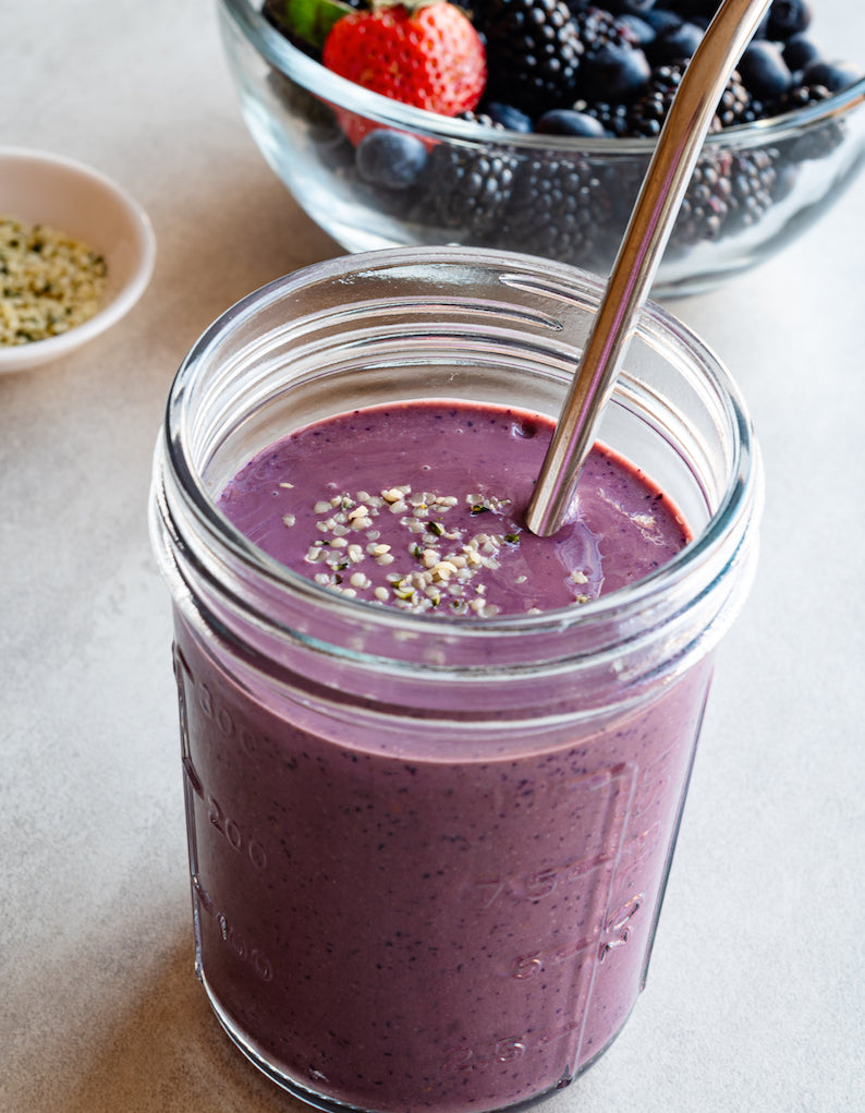 Mixed berry smoothie with berries in the background