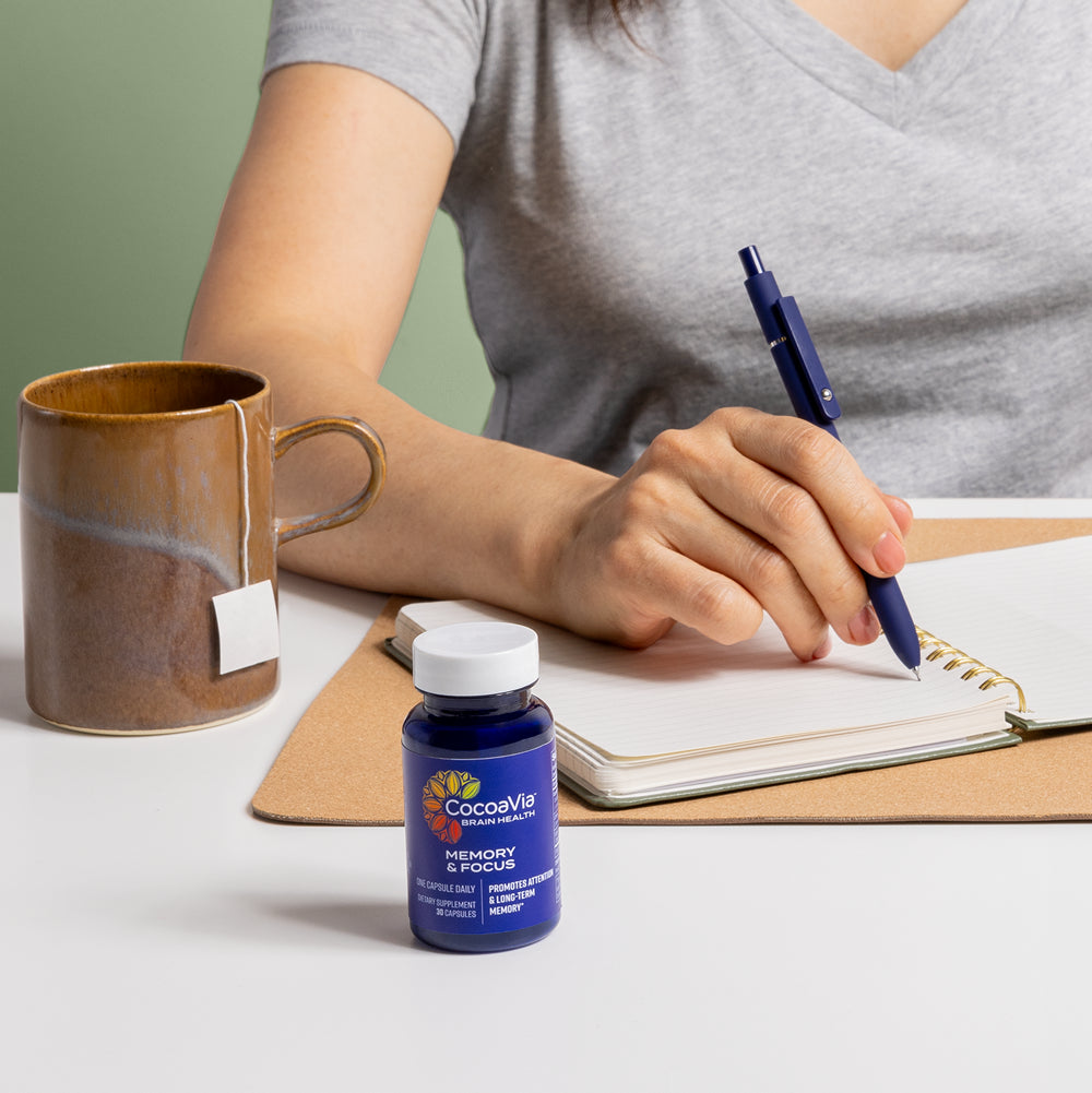 Model Writing In Notebook With Bottle Next To Them