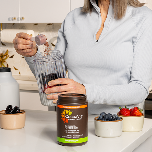 Woman pouring berries into smoothie