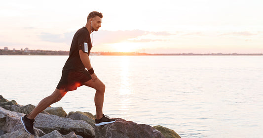 Man stretching leg muscles on rocky shore
