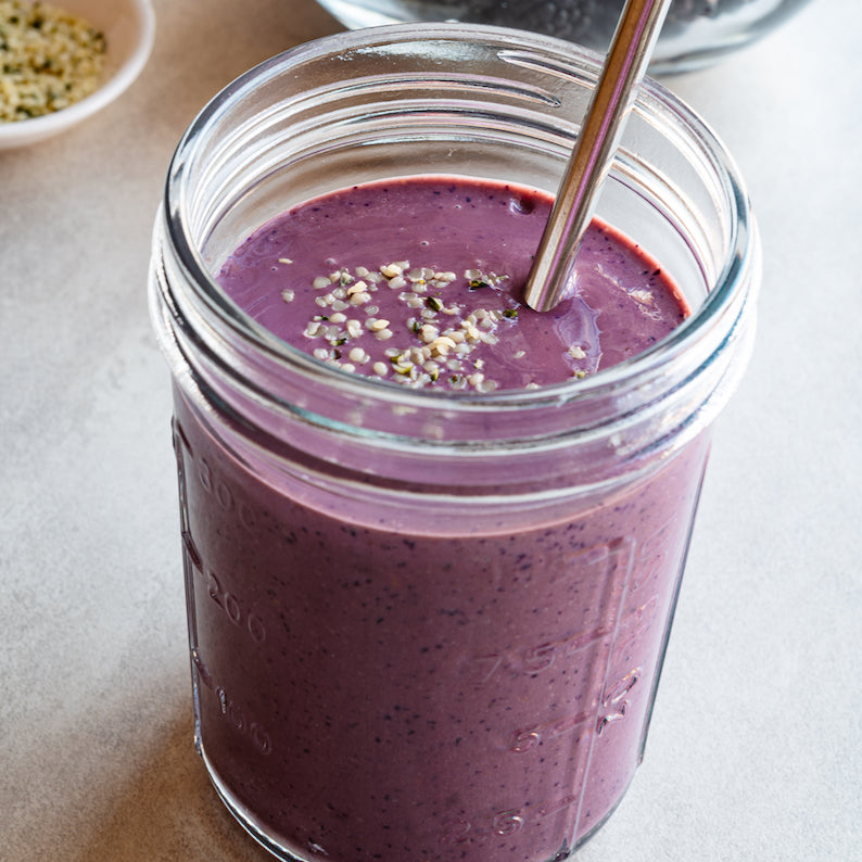Mixed berry smoothie with berries in the background