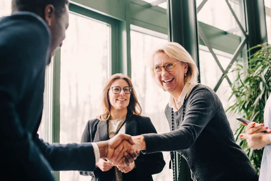 Older woman in business setting shaking hands with a business colleague