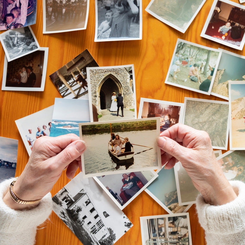 hand holding a picture with a bunch of pictures in the background