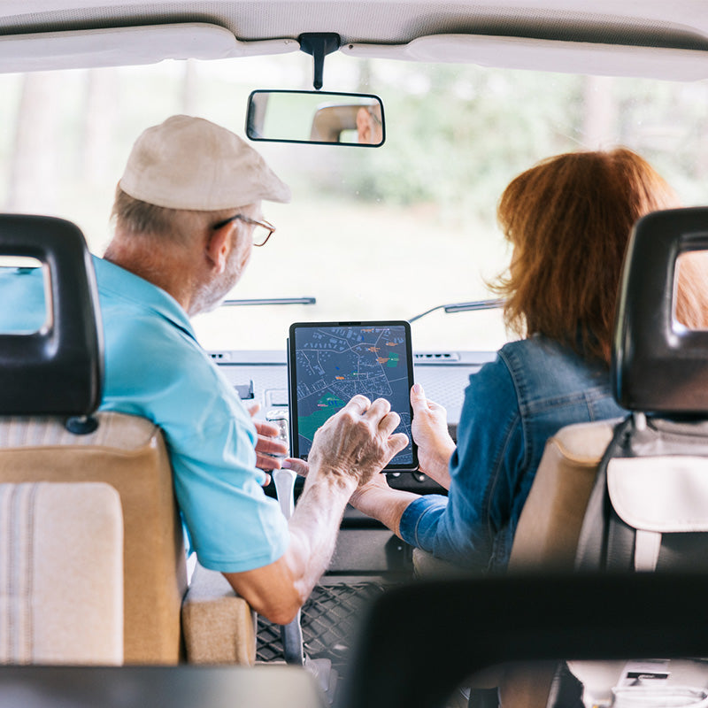 Elderly couple navigating on a map on ipad in car