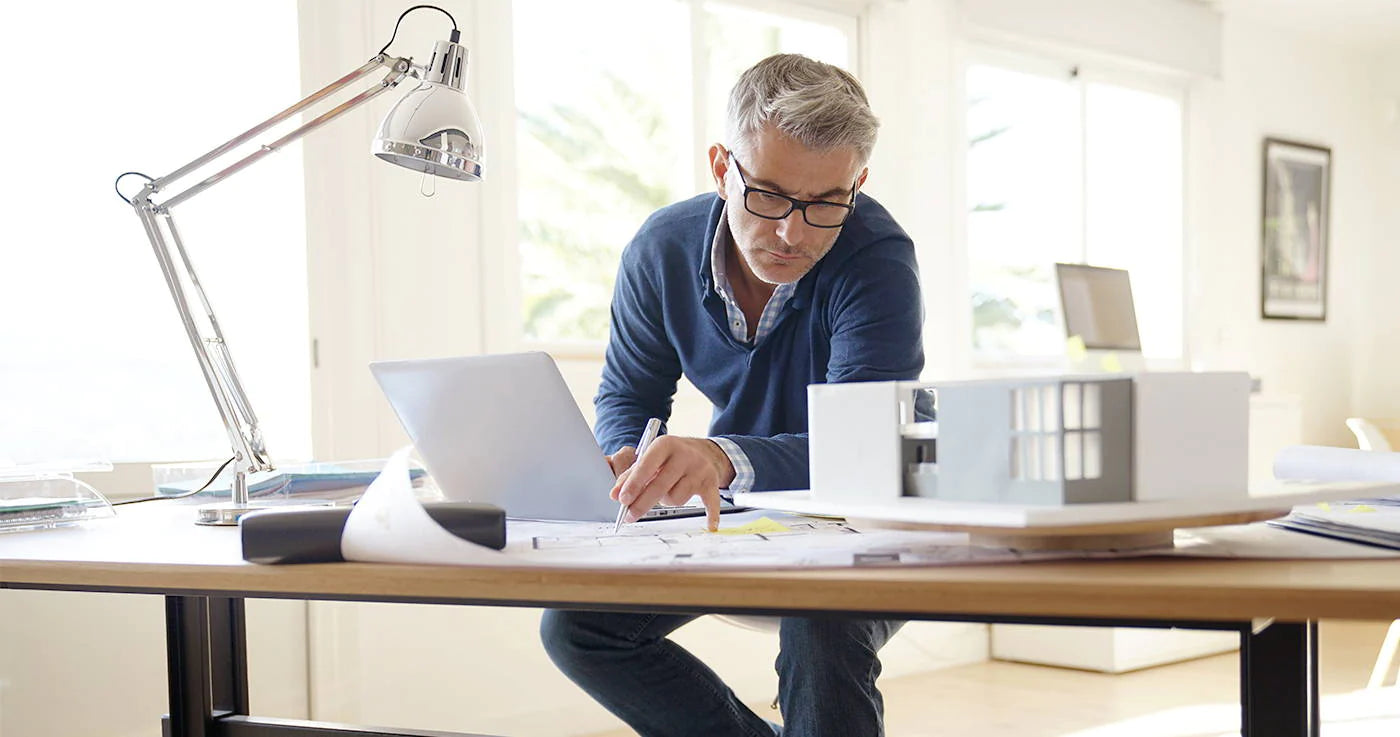 Elderly man with glasses working on desk