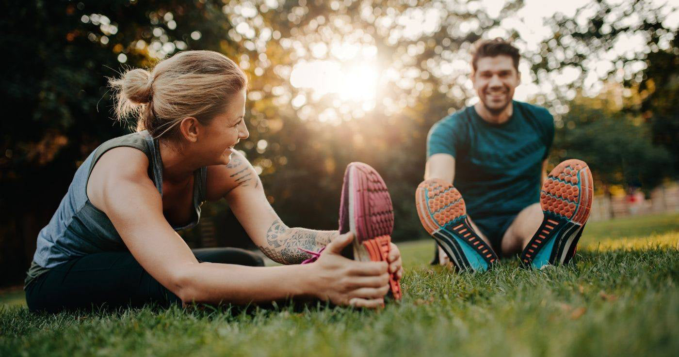 woman and man stretching on grass